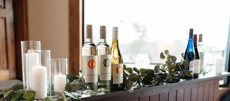 Wine bottles, candles, and eucalyptus styled along the bar