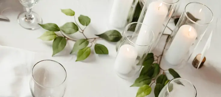 Pillar candles and greenery styled on a white linen table