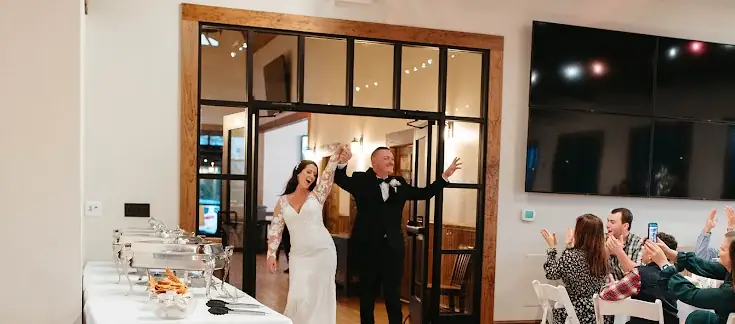 Newlyweds entering their wedding reception to applause from guests
