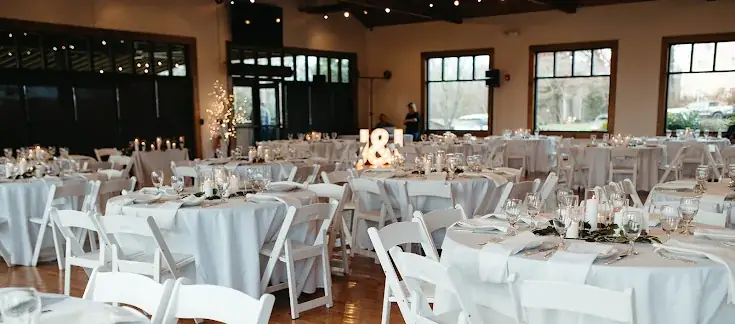 Wedding reception with white linens, greenery, and candlelight