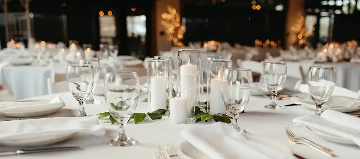 Wedding table setting with candles, greenery, and glassware